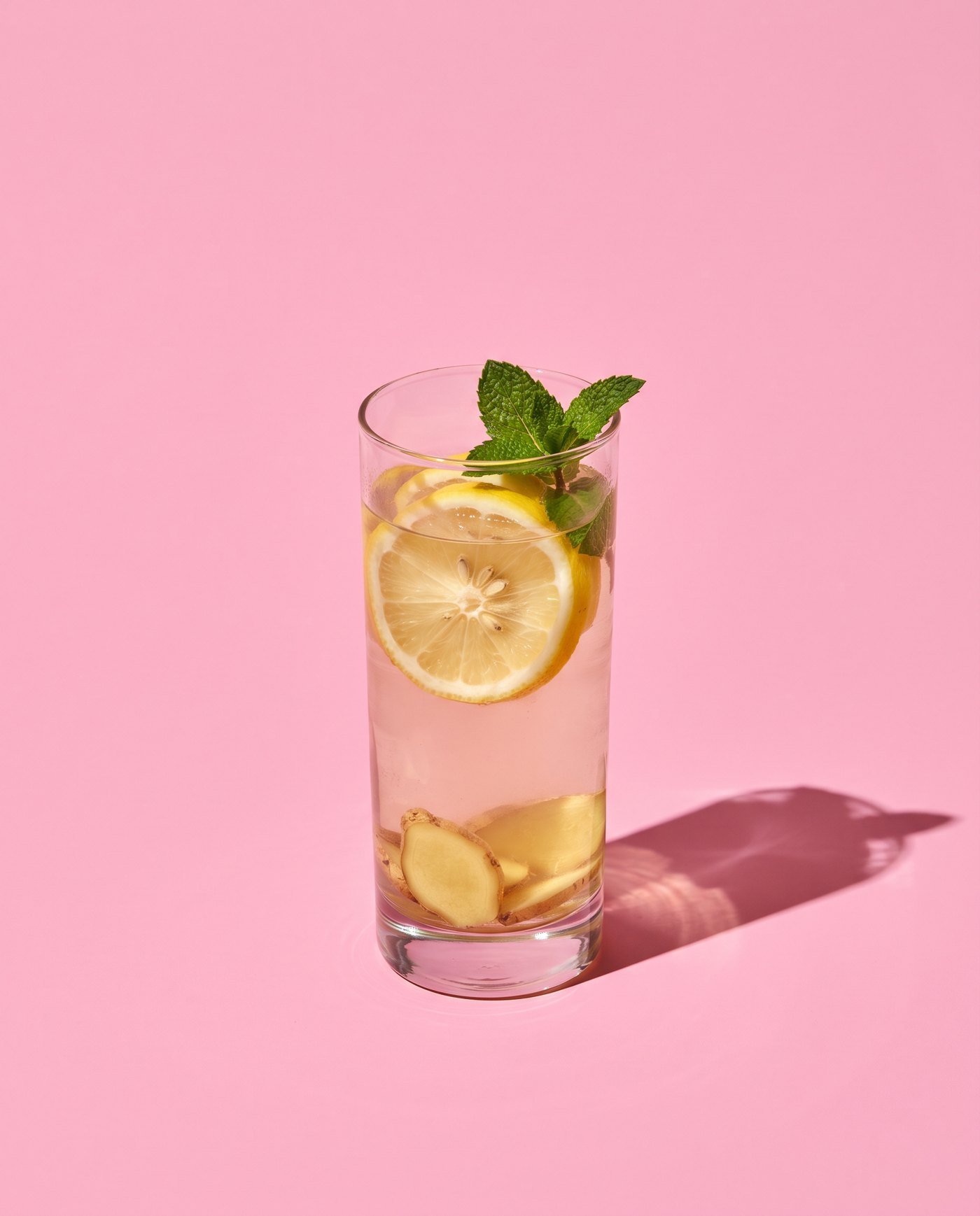 A glass of warm water with lemon, ginger and mint