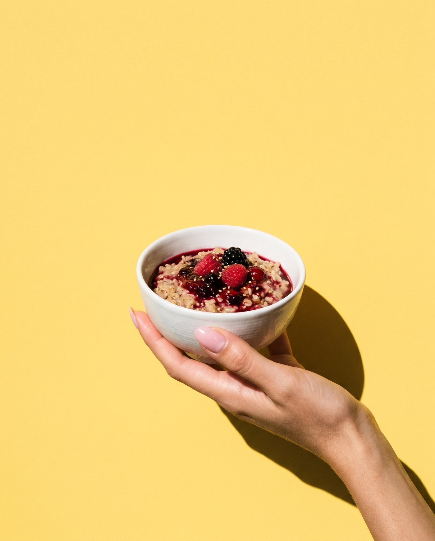 A hand holding a bowl of berry porridge