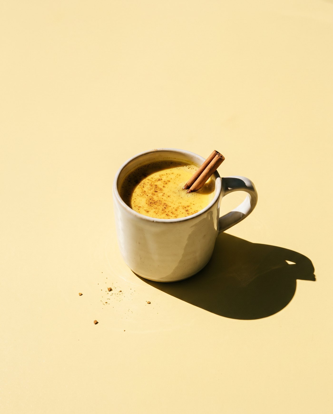 A mug of warm golden milk with a cinnamon stick